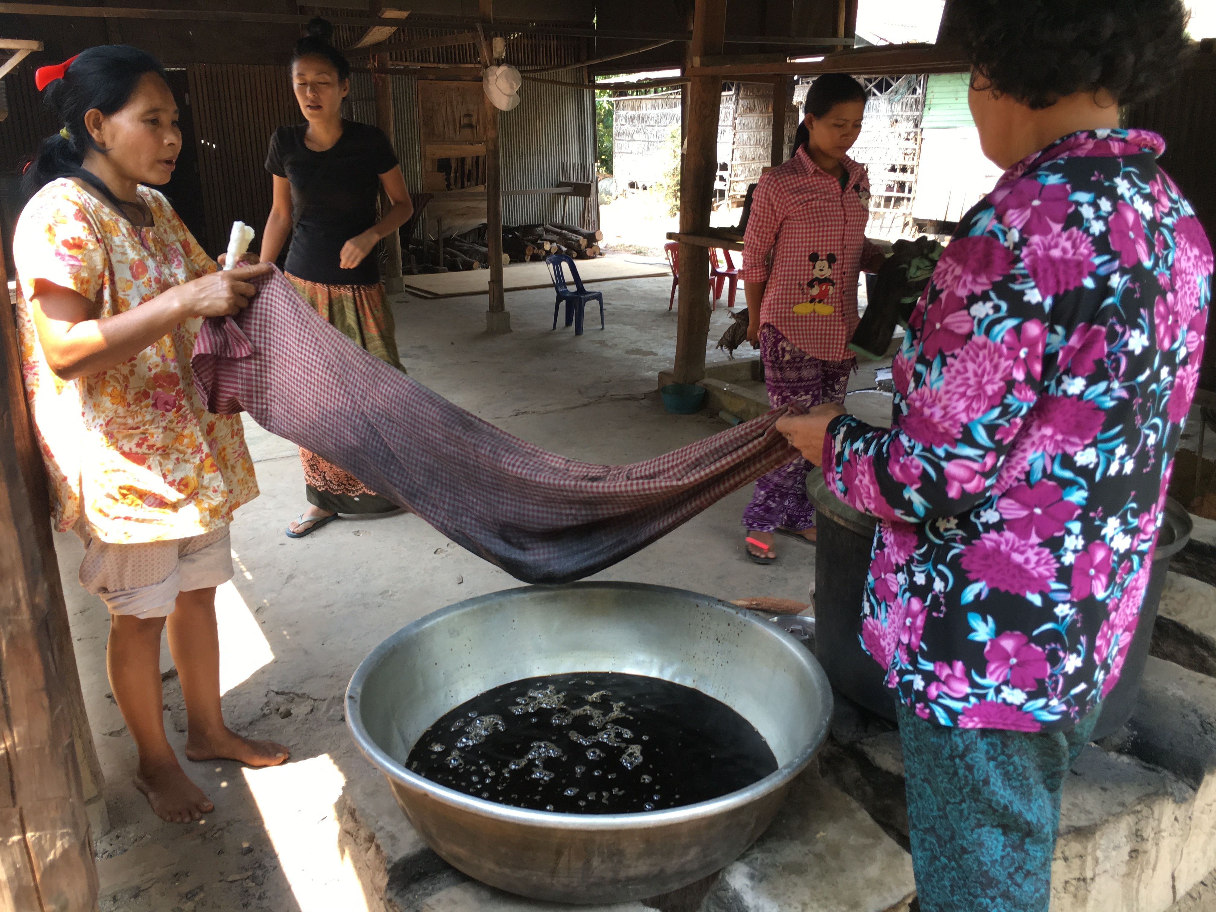 染色作業をする村の女性たち。大きな鍋に入った天然染料で布を染めている