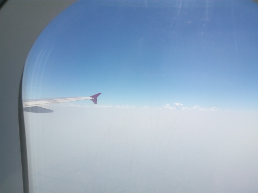 機内の窓から見た空。雲の上を飛ぶLCCの翼