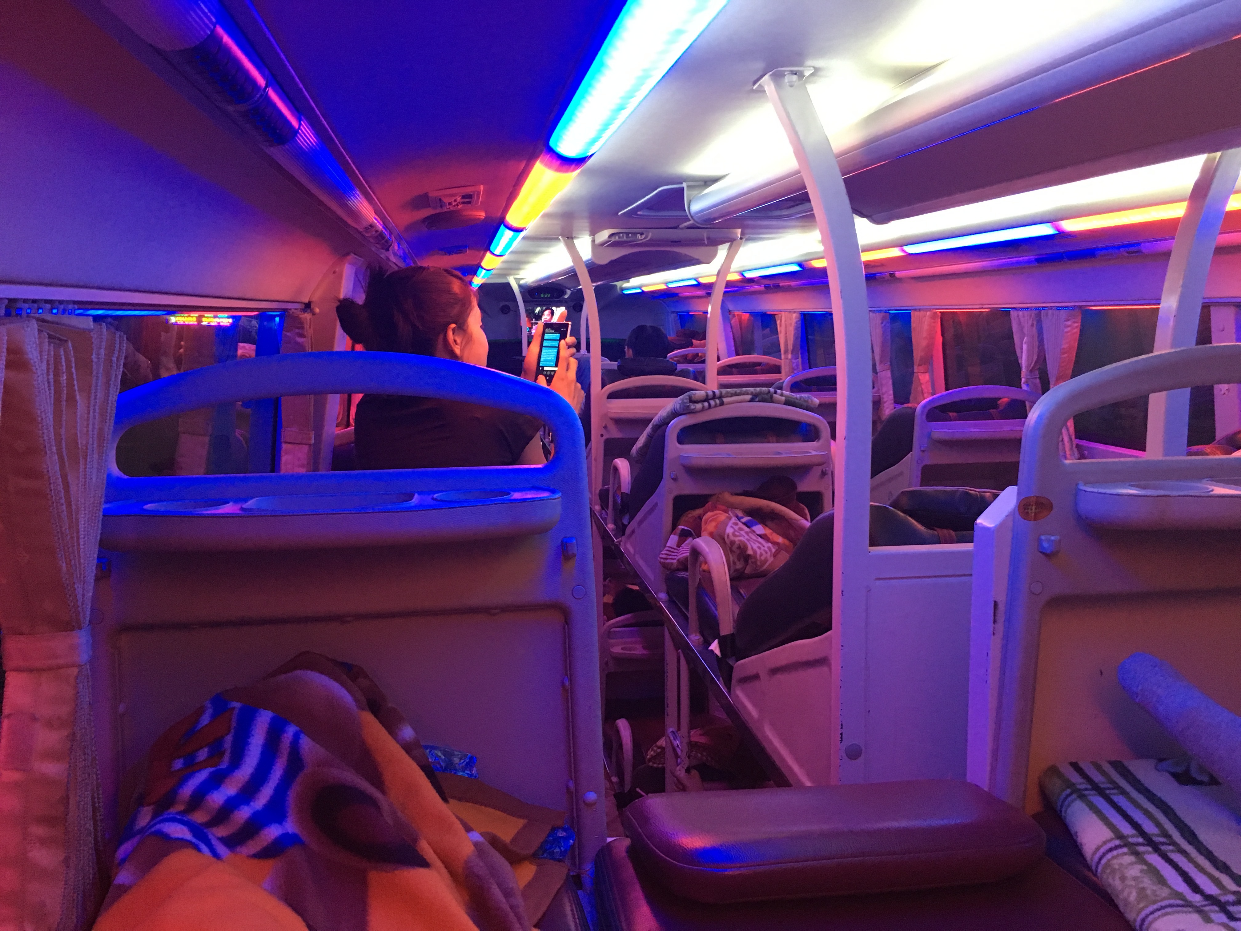 紫やピンクのライトに照らされた、ラオス行き夜行バスの車内