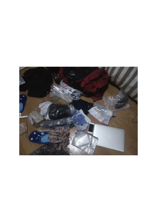 出発前日、部屋の床に広げた実際の荷物。赤いモンベルのバックパック、MacBook、サンダル、圧縮袋に詰めた衣類……これが全部だった。