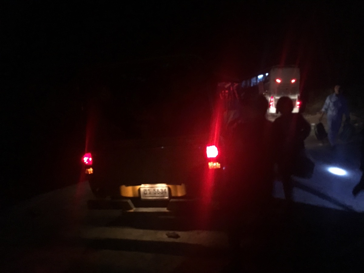夜道を進む車のテールランプ。荷物を抱えて移動する乗客たち