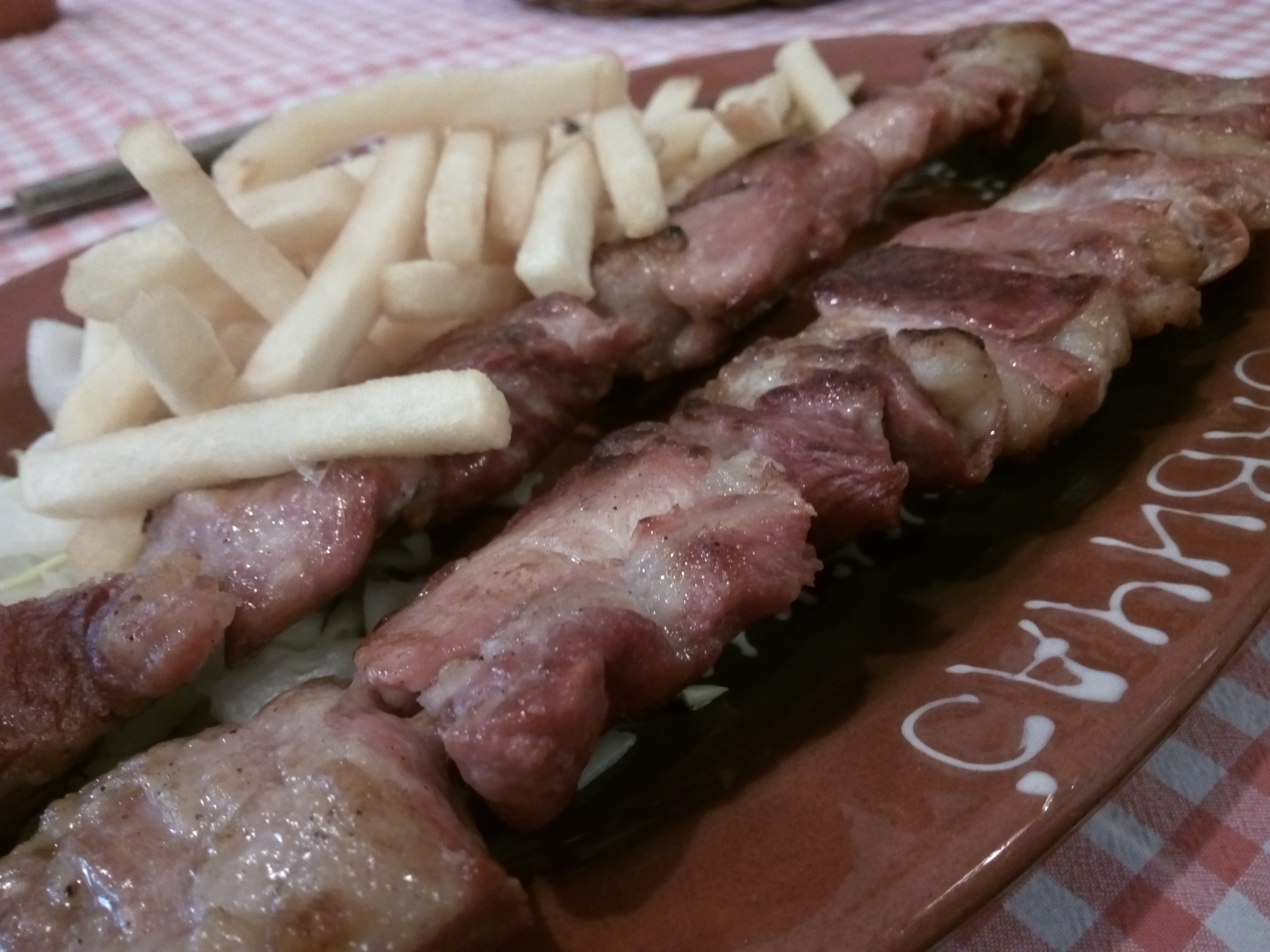 燻製ポークのBBQグリル。ジューシーな肉がプレートいっぱいに並び、フライドポテトが添えられている
